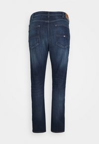 Tmavě modré džínové kalhoty se střihovým střihem nohavic, dvěma zadními kapsami, prošíváním a hnědou koženou štítkem na pásu.