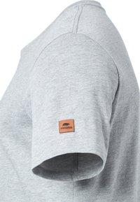 Camiseta gris de manga corta hecha de tejido suave, con una costura de hombro cosida y un parche de logo marrón en la manga izquierda.
