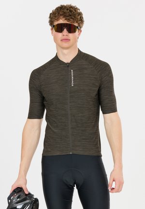 Nuori mies, joka pukeutunut tummaan pyöräilypaitaan ja shortseihin, pitää pyöräilykypärää ja käyttää heijastavia urheilulaseja.