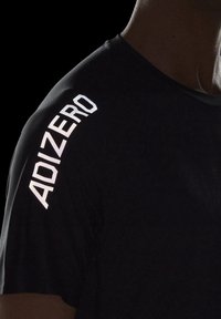 Svart tränings t-shirt med en strukturerad tyg. Framträdande reflekterande "ADIZERO"-logotyp i kraftigt vitt längs vänster axel.