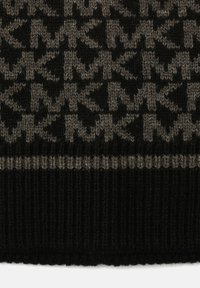 Tissu tricoté noir et gris avec un motif géométrique en zigzag et un ourlet noir côtelé au bas.