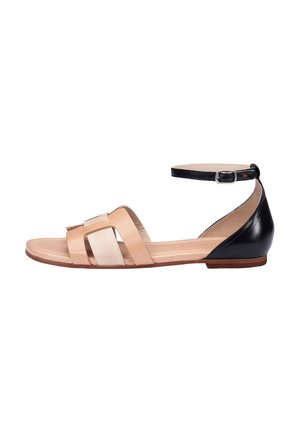 Sandalias planas con tiras en una combinación de cuero nude y negro, que cuentan con una correa para el tobillo y un acabado suave y pulido.