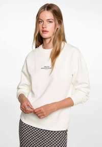 Light cream sweatshirt with ribbed cuffs and hem, featuring embroidered text reading "TIMELESS NOSTALGIA CULTURE" in black.