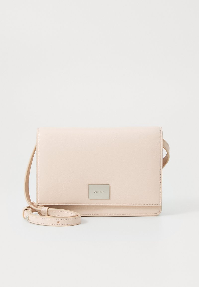 Gaiši rozā sintētiskās ādas maks ar salokāmu vāciņu, atdalāmu plaukstas siksniņu un sudraba logo plāksni priekšpusē. Gluda virsma.