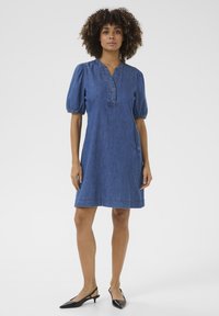 Denim dress with a collared neckline, short puff sleeves, and a relaxed fit. Solid blue color with a subtle hemline and side pockets.