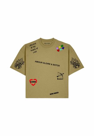Beiges T-Shirt mit schwarzen Textphrasen, bunten kleinen Patches, flammenden Würfeln auf den Ärmeln, rotem Herz mit "Karma," und Pfeil mit "Lover" Grafik.