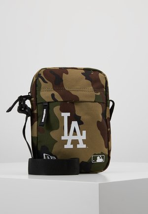 Borsa a tracolla camouflage realizzata in tessuto durevole. Caratterizzata da un logo LA bianco, una tracolla regolabile e una chiusura superiore con zip. Forma quadrata.