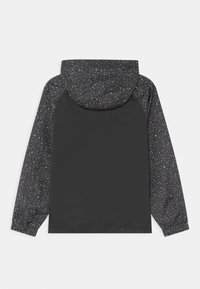 Chaqueta impermeable negra con capucha y mangas de patrón moteado y acentos rojos y blancos, puños elásticos y dobladillo ajustable.