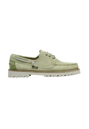 Chaussure bateau en daim vert clair avec lacets à l'avant, semelle blanche épaisse à rainures et étiquette de marque latérale sur fond blanc.