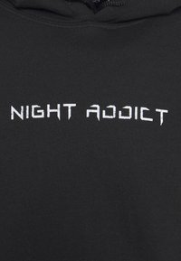 Sweat à capuche noir avec texte usé blanc "NIGHT ADDICT" centré sur la poitrine, avec un cordon visible près du col.
