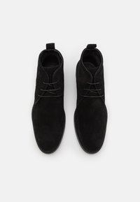 Bocanci scurți din suede negru cu o finisare netedă, vârf rotund și design cu șireturi; prezintă o bucată de tragere în partea din spate pentru a fi ușor de încălțat.