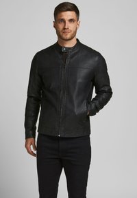 Veste en cuir noir avec col montant, fermeture éclair �à l'avant et poches latérales. Finition texturée et détails de surpiqûres subtils. Design slim fit.