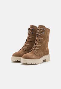 Botas de ante marrón hasta el tobillo con diseño de cordones, punta redonda y suela de goma color crema con textura para un mejor agarre.