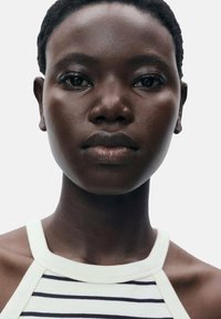 Portrait of a person with dark skin, short hair, and a striped sleeveless top. Features include smooth skin and distinct facial structure.