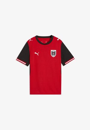 Raudonas trumpomis rankovėmis futbolo marškinėlis su juodomis rankovėmis, priekyje yra Puma logotipas ir Austrijos futbolo asociacijos emblema. Lygus audinys.