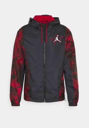Sort og rød hættejakke med fuld lynlås, røde snore og stjerne-logo med en basketballspiller på venstre bryst.