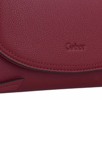 Clutch de piel burdeos con un acabado texturizado, que presenta una solapa curva y el logo grabado "Gabor". Un sutil pespunte negro resalta el diseño.