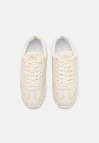 Valkoiset nahkakengät, joissa pyöreä kärki, suorat nauhat, hienovarainen tekstuuri ja pehmustettu sisäpohja. "cK"-logo painettuna kielekkeeseen.