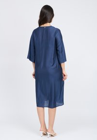 Marineblaues Midi-Kleid aus einem glatten, leichten Stoff. Mit 3/4-Ärmeln und einem runden Ausschnitt mit einem kleinen Knopfdetail auf der Rückseite.