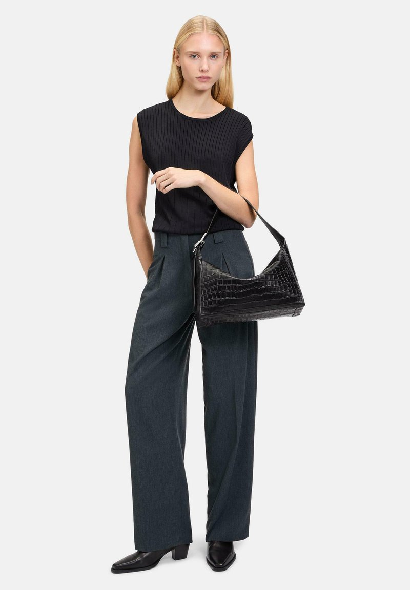 Haut noir côtelé avec des manches courtes, pantalon large gris foncé ajusté et sac noir à motif crocodile. Escarpins noirs à bout pointu.
