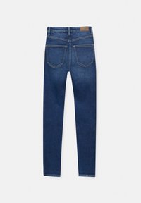 Jean skinny bleu foncé étalé à plat montrant le dos avec deux poches et un patch en cuir de la marque sur la ceinture.