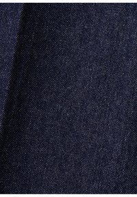 Gros plan d'un tissu denim bleu foncé montrant une texture de tissage diagonal avec des taches de fil blanc.