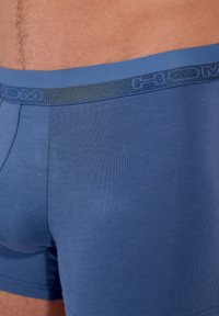 Blå boxershorts i stretchtyg med en kontrasterande blå resårmidja med en enkel logotyp. Slät struktur med en figurnära design.