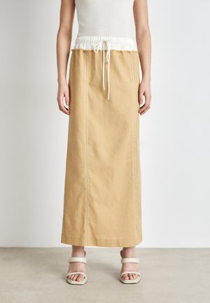 Lång, beige kjol med vit elastisk midja och snörning. Har rak passform, sidsömmar och ett subtilt texturerat tyg.