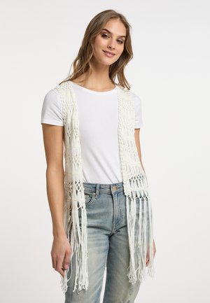 Valkoinen virkattu avointa etuosa liivi, jossa on fringed yksityiskohtia, valmistettu kevyestä langasta. Käytetään yksinkertaisen valkoisen t-paidan ja vaaleansinisien farkkujen päällä.