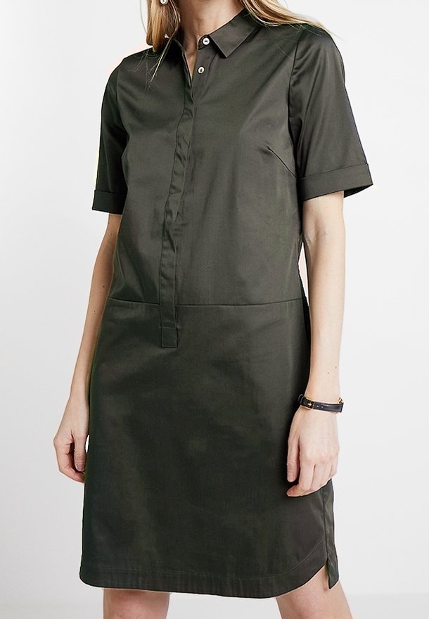 Sukienka z krótkim rękawem w ciemnozielonym kolorze, wykonana z gładkiej tkaniny. Posiada kołnierzyk, zapinana na guziki z przodu oraz ma boczne rozcięcia, które ułatwiają ruch.