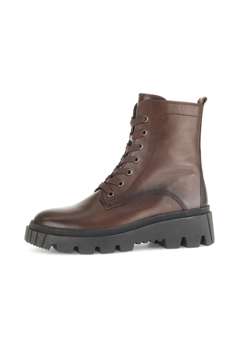 Botas de cuero marrón hasta el tobillo con punta redonda, suela de goma negra gruesa y seis ojales para los cordones. Cuenta con una lengüeta en la parte trasera para facilitar su uso.