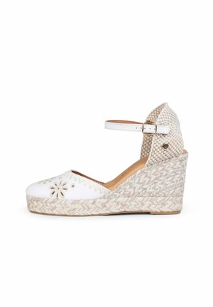 Alpargata de cuña blanca con recortes florales en la puntera, plataforma de yute tejido, correa al tobillo con hebilla y talonera texturizada.