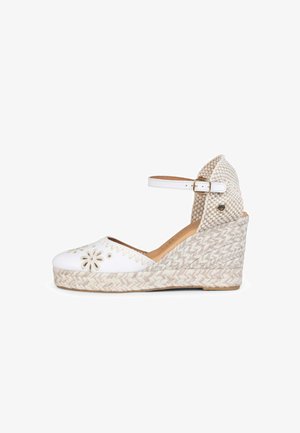 Alpargata de cuña blanca con recortes florales en la puntera, plataforma de yute tejido, correa al tobillo con hebilla y talonera texturizada.
