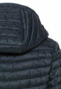 Dunkelblau gesteppte Jacke mit gepolsterter Kapuze und Oberrücken, versehen mit horizontalen Steppnähten.