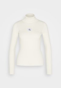 Maglione bianco a collo alto a costine con maniche lunghe e design aderente, caratterizzato da un piccolo patch con il logo CK sul petto.