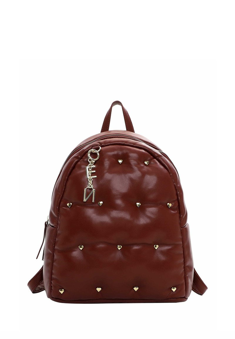 Sac à dos matelassé marron avec des clous en forme de cœur dorés et un charm en forme de lettre dorée suspendu près de la fermeture éclair supérieure.