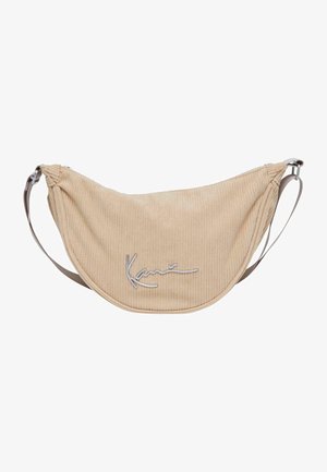 Beige corduroy schoudertas met zilveren hardware en "Kani" logo. Gebogen, zachte vorm met verstelbare band. Textuur met verticale lijnen.