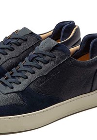 Navy leather sneakers with textured and smooth finishes, featuring lace-up design, low-profile sole, and contrasting tan accents.