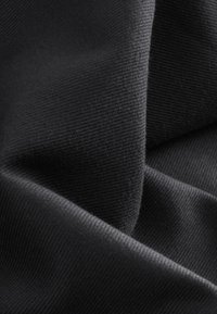 Czarny tkanina o fakturze z gładkim wykończeniem, z delikatnym prążkowanym wzorem. Materiał wydaje się miękki i elastyczny, z widocznymi fałdami.