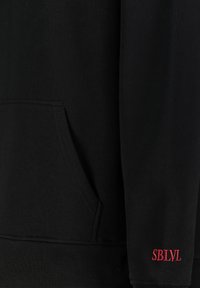 Black hoodie with a front pocket, ribbed hem, and embroidered red "SBLVL" logo on the sleeve. Made of soft, textured fabric.