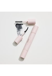 Dubbeländad rosa maskaratub med två distinkta borstar och en svart maskaraskvätt på en vit yta.