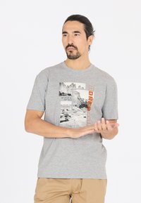 Harmaa puuvillapaita, jossa on graafinen printti vuorista ja koordinaateista, oransseilla ja mustilla tekstikorostuksilla. Pyöreä kaula-aukko, lyhyet hihat.