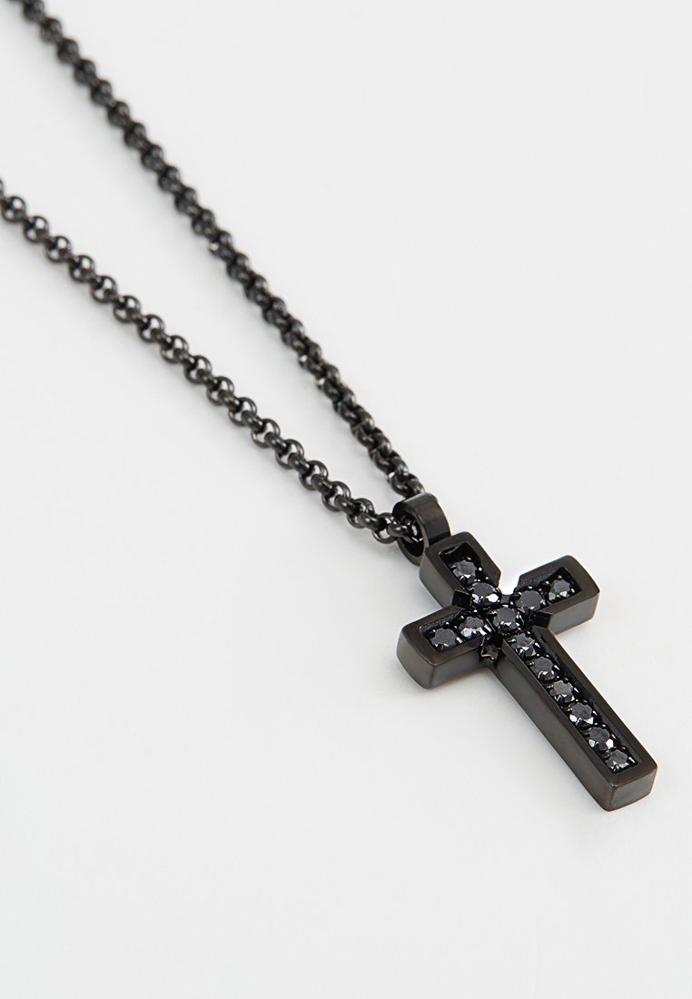 Collana con pendente a forma di croce nera con superficie testurizzata, caratterizzata da pietre nere incastonate lungo il centro, sospesa a una catena nera.