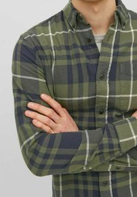 Grünes und marineblau kariertes Flanellhemd mit langen Ärmeln, Knopfkragen, Brusttasche und weißen Akzenten auf den Karos. Glatte Textur.