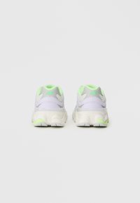 Baskets de sport en violet clair avec des accents gris, dotées d'une semelle rembourrée, de panneaux en maille et de détails verts fluo sur le talon et le logo.