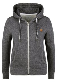 Sudadera gris con cremallera, capucha con cordón, puños acanalados y dos bolsillos frontales. Presenta un pequeño logotipo en el lado izquierdo del pecho. Tejido de textura suave.