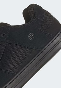 Černé tenisky s horní částí z prodyšného materiálu a syntetickými akcenty, zaoblená špička, plochá podrážka a diskrétní logo. Hladký povrch s elegantním designem.