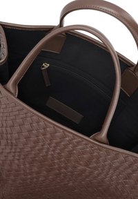 Καφέ υφασμάτινη τσάντα tote με δύο λαβές, εσωτερική επένδυση από μαύρο ύφασμα και τσέπη με φερμουάρ για ασφαλή αποθήκευση.