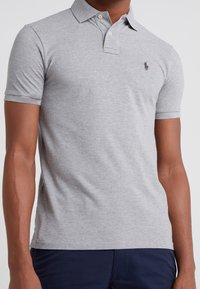 Polo shirt in cotone grigio con maniche corte e colletto a punta. Presenta un piccolo logo ricamato sul petto e bottoni sul colletto.