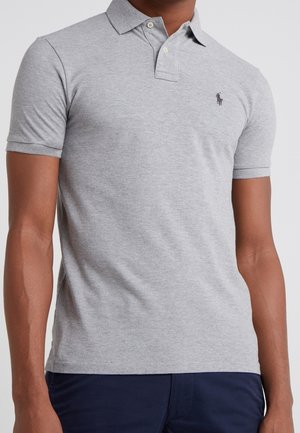 Polo en coton gris à manches courtes et col pointu. Présente un petit logo brodé sur la poitrine et des boutons au col.